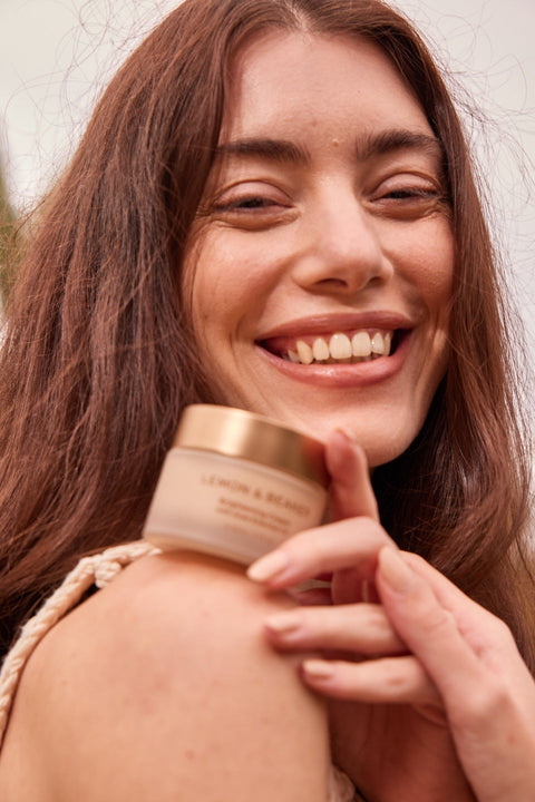 Woman Smiling while Holding the Lemon and Beaker Brightening Cream 