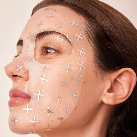 A woman wearing a sheet mask featuring silver-colored lines throughout.